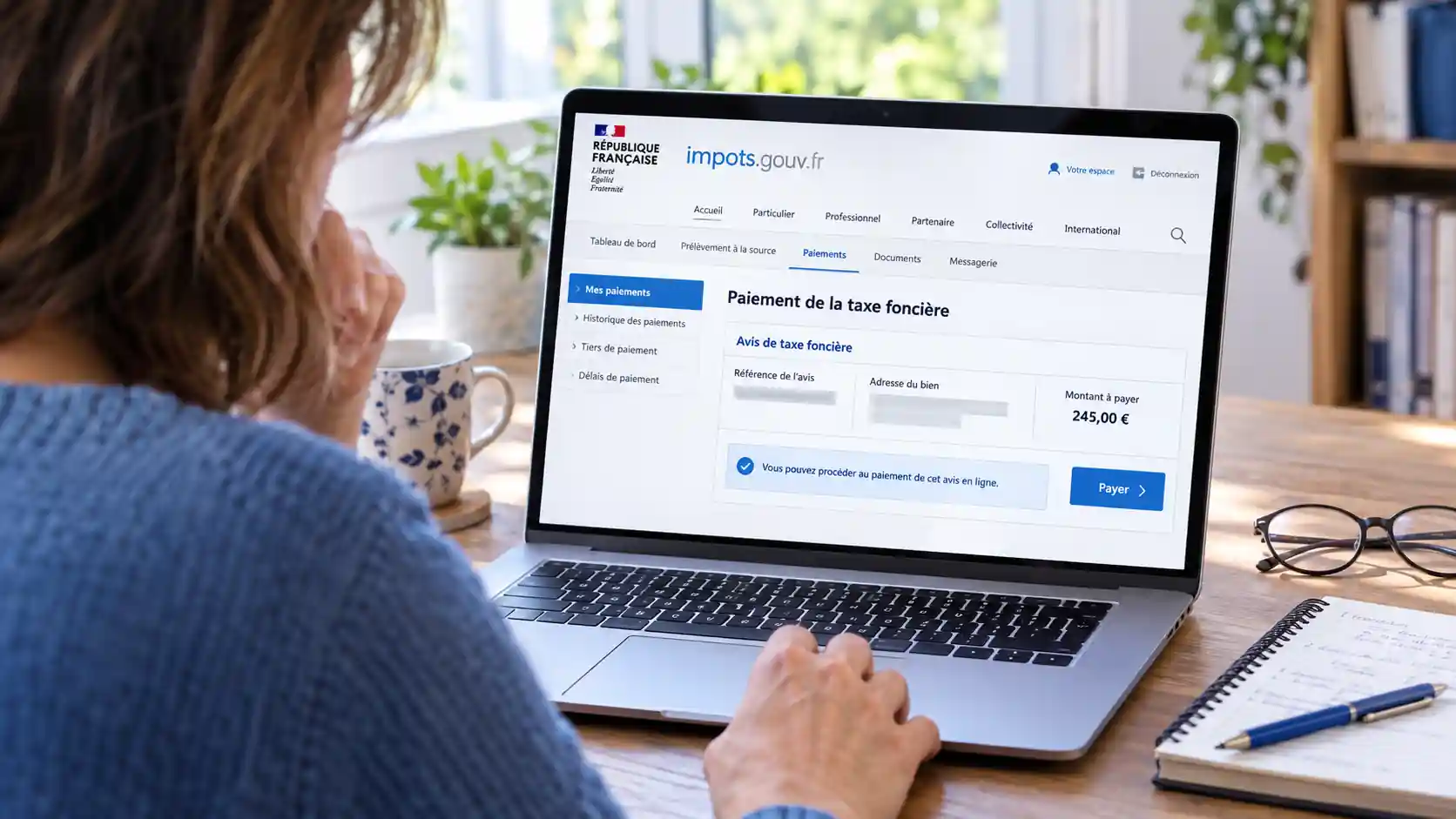 Femme payant sa taxe foncière en ligne depuis son espace personnel sur impots.gouv.fr, avec l’onglet Paiements affiché sur son ordinateur.